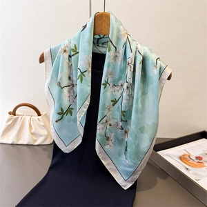 Floral print faux silk scarf with elegant white magnolia pattern on light blue fabric