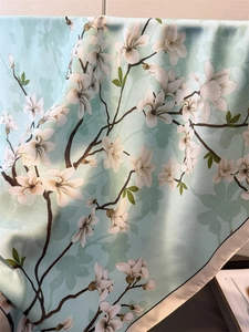 Detailed view of silk scarf with elegant mint green magnolia floral pattern and smooth texture