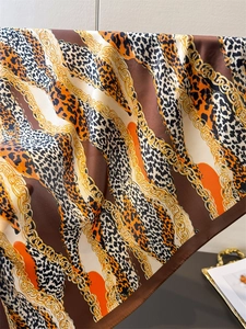 Close-up of leopard and gold chain print silk scarf showing drape and satin texture
