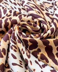 Macro view of spiral leopard print silk satin fabric showing glossy smooth texture
