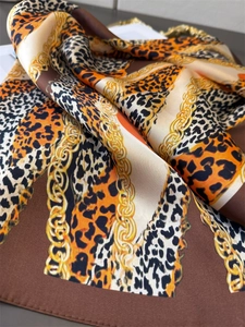 Macro detail of silky scarf fabric featuring leopard print and golden chain patterns
