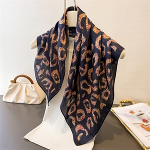 Detail of leopard print silk scarf draped over a stand showing texture and pattern