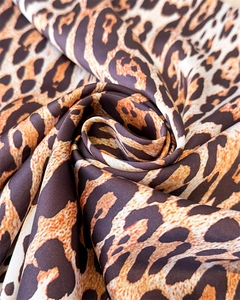 Close-up of silk leopard print scarf showing soft satin texture and warm orange tones