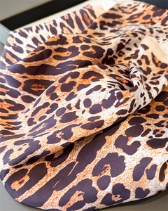 Close-up of leopard print faux silk scarf showing smooth texture and soft drapes