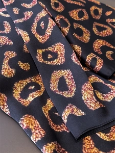 Macro shot of leopard print silk scarf showing glossy texture and fine hemmed edges