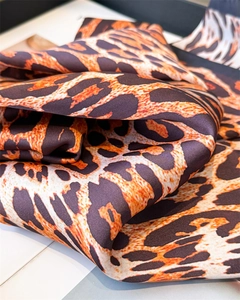 Detailed close-up of leopard print silk scarf fabric with smooth satin texture