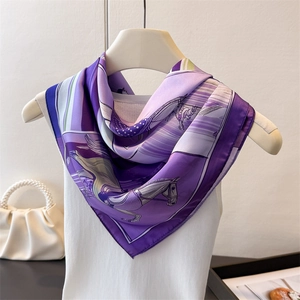 Détail d'un foulard en soie violette avec imprimé équestre porté sur un haut blanc