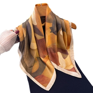 Eleganter Seidenschal mit geometrischem Kunstdruck an einem Holzkleiderbügel hängend