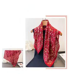 Gros plan du foulard en soie rouge à motifs floraux montrant la texture du tissu premium