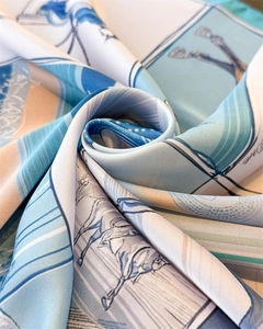 Détail macro du foulard en soie montrant des imprimés équestres bleu ciel et beige