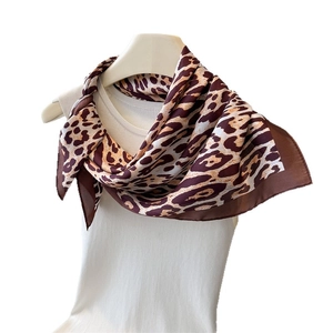 Leopard print silk square scarf styled on a white mannequin neck with a neutral aesthetic
