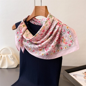 Gros plan détaillé d'un foulard en soie rose à fleurs sur un débardeur noir en maille