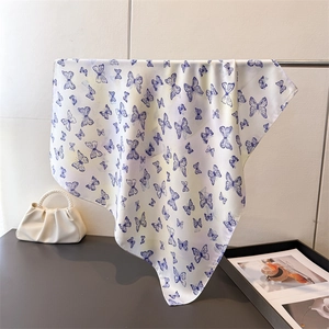 Detail showing white silk scarf with blue butterfly print hanging on a metal rod