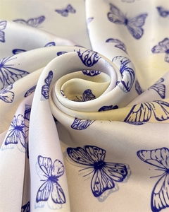 Artistic close-up of blue butterfly print on white silk scarf with smooth satin texture