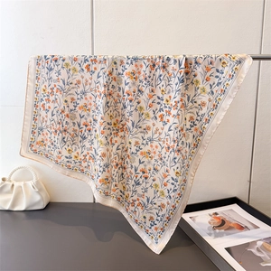 Détail d'un foulard carré en soie à imprimé floral avec des bords finement surpiqués