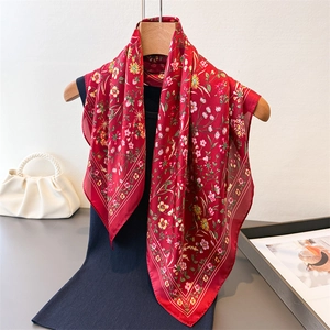 Carré de soie rouge à fleurs élégant sur un cintre en bois avec une robe bleu marine