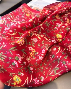 Détail d'un foulard en satin rouge aux motifs floraux et bords rayés élégants
