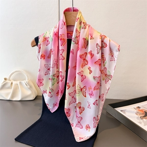 Pink and white gradient silk scarf with butterfly print hanging on a wooden hanger