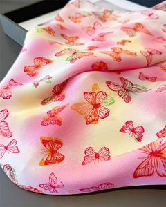Detailed shot of vibrant butterfly print silk scarf with gradient pink to yellow hues