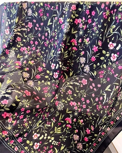 Vue détaillée du motif floral sur foulard en soie noire avec bordure délicate