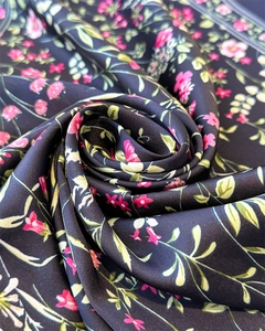 Vue macro d'un tissu soyeux à imprimé floral avec fleurs roses sur fond noir