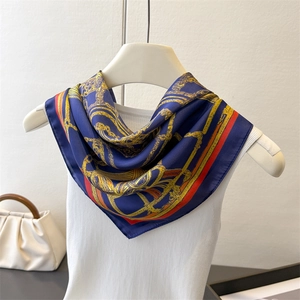 Détail d'un foulard en soie avec motifs de chaînes dorées et design baroque bleu marine