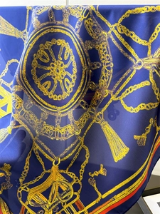 Détail d'un foulard en soie avec chaînes dorées et motifs nautiques sur fond bleu marine