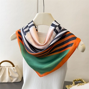 Geometric striped silk-like square scarf in vibrant orange and green on a white hanger