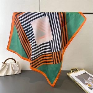 Detail of colorful geometric silk scarf with hand-rolled edges on a designer handbag