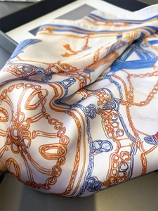 Gros plan d'un foulard en soie avec motif de chaîne dorée et cordage bleu royal