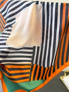 Detail of soft silk-like scarf with geometric orange stripes and green color blocks