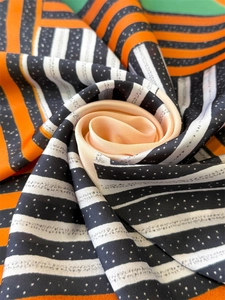 Macro detail of silk-like scarf folded into a rose shape showing orange and black stripes
