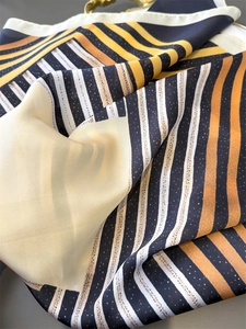 Detailed close-up of geometric striped silk scarf with orange and black patterns