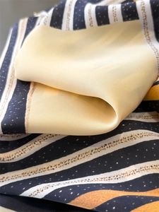Macro view of geometric striped silk scarf showing soft drape and lustrous texture