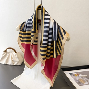 Silk-like square scarf with geometric red and gold stripes shown on a mannequin