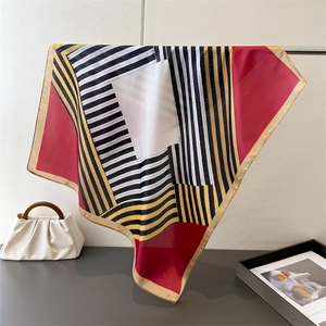 Detailed view of silk-like square scarf with geometric stripes and golden hem edges