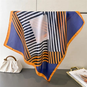 Detailed view of large silk scarf featuring geometric stripes and orange border patterns