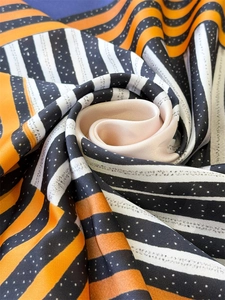 Detailed view of striped geometric silk scarf with smooth satin texture and elegant drape