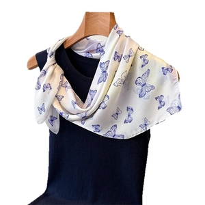 Elegant cream silk scarf with blue butterfly print tied on a black vest display
