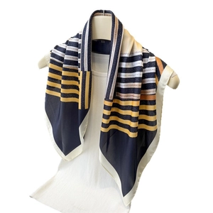 Navy blue and yellow geometric striped silk-like scarf draped on a mannequin