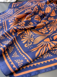 Detail eines Seidenschals mit marineblauem und orangefarbenem Blumenmuster