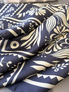 Detail eines Seidenschals mit marineblauem Blumendruck und elegantem Satenglanz in Falten