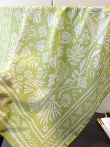 Nahaufnahme eines hellgrünen Seidenschals mit Blumenmuster und elegantem Satin-Glanz