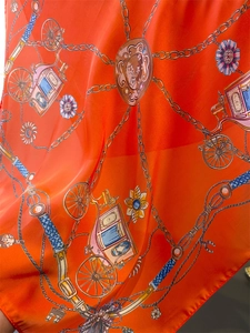 Detail eines luxuriösen orangefarbenen Seidenschals mit klassischem Kutschenmotiv