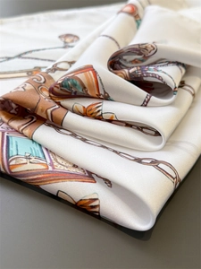 Detail eines Seidenschals mit Reitsport-Druck und glänzender Satin-Textur