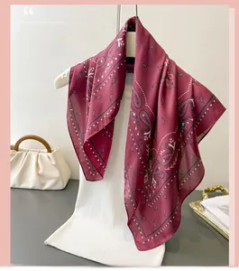 Elegant burgundy paisley silk-like scarf draped over a hanger with stylish bag detail