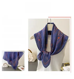 Detail of navy blue silk-feel scarf with orange paisley prints styled on a white mannequin