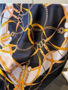 Macro detail of silk scarf showing equestrian chain print and smooth fabric texture