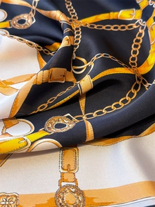 Detailed view of luxury equestrian chain print on smooth black and gold silk scarf