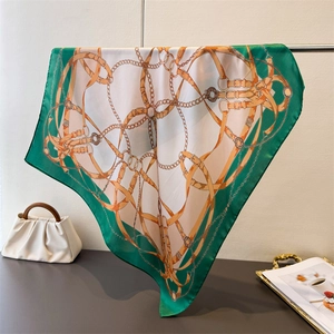Detailed view of luxury emerald chain print silk scarf draped over a gold metal stand